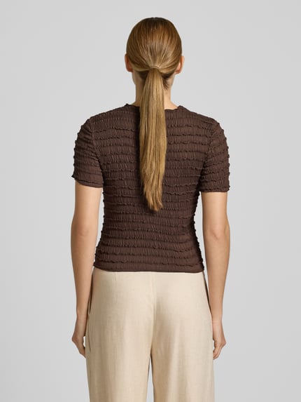 Frauenmodel trägt T-Shirt mit Strukturmuster und Rundhalsausschnitt von Jake*s Collection in Braun, Material-Mix mit Stretch, Ganzkörperansicht Rückansicht.
