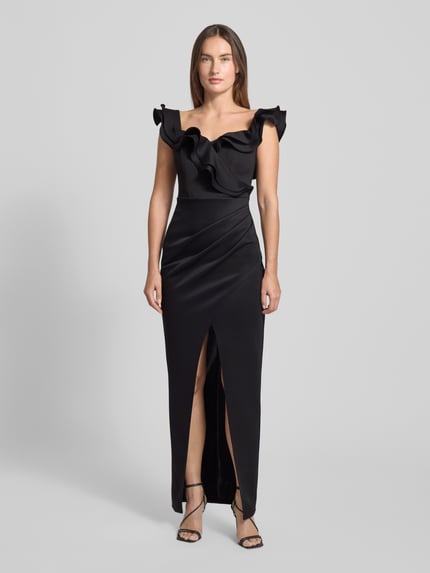 Kobiece modelka nosi czarne Abendkleid mit Volants von Lipsy, materiał elastyczny, dekolt kwadratowy, rozcięcie, widok całej sylwetki z przodu.
