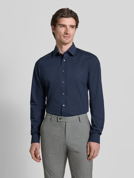 Männermodel trägt Regular Fit Businesshemd mit extra langem Arm von OLYMP Level Five, unifarben, Kentkragen, Ganzkörperansicht von vorne.