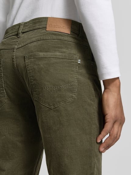 Mężczyzna nosi Cordhose aus Baumwoll-Mix im 5-Pocket-Design von Christian Berg Men, kolor oliwkowy, tekstura sztruksowa, krój slim fit, zapięcie na guzik i zamek, Szerokość w rozmiarze 32/32: 43 cm, długość nogawki wewnętrznej: 79 cm, widok z tyłu, zbliżenie na biodra
