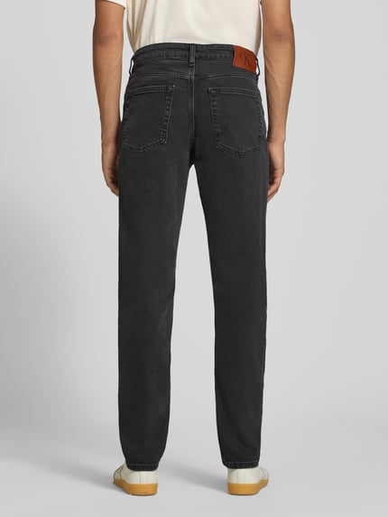 Mannenmodel draagt Slim Fit Jeans uit katoenmix van Calvin Klein Jeans in het zwart, rechte pijpen, textuurrijke stof. Volledig aanzicht achteraan.