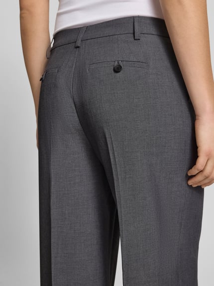 Frauenmodel trägt Wide Fit Stoffhose mit Viskose-Anteil von Gina Tricot in Grau mit Gesäßtaschen und Bügelfalten, Nahaufnahme Rückansicht.
