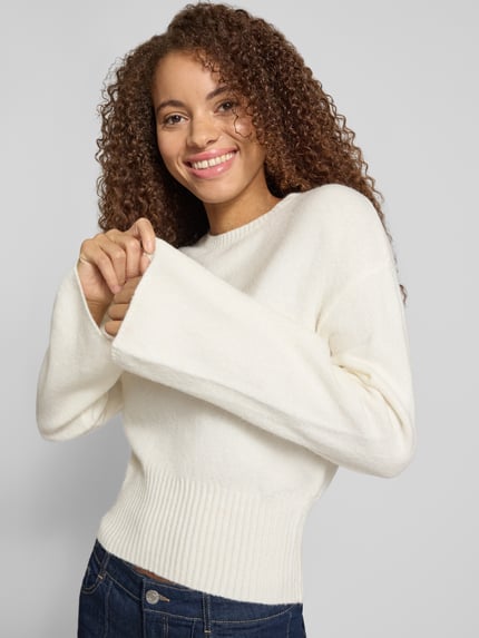 Frauenmodel trägt Pullover mit ausgestelltem Ärmelabschluss von ONLY, unifarben, cropped, Strick, Nahaufnahme Oberkörper.