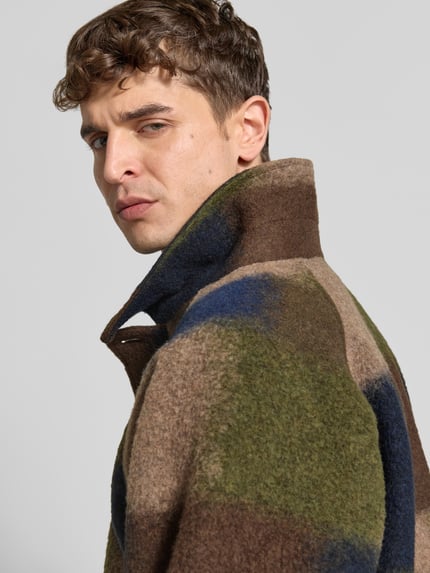Männermodel trägt Jacke mit Woll-Anteil von Forét in Braun, Blau und Grün, sichtbarer Material-Mix, Nahaufnahme Oberkörper. Regular Fit, durchgehende Knopfleiste, Pattentaschen, verstellbare Ärmelriegel, Rückenlänge bei Größe M 71 cm, Schulterbreite 45 cm, Ärmellänge 71 cm.