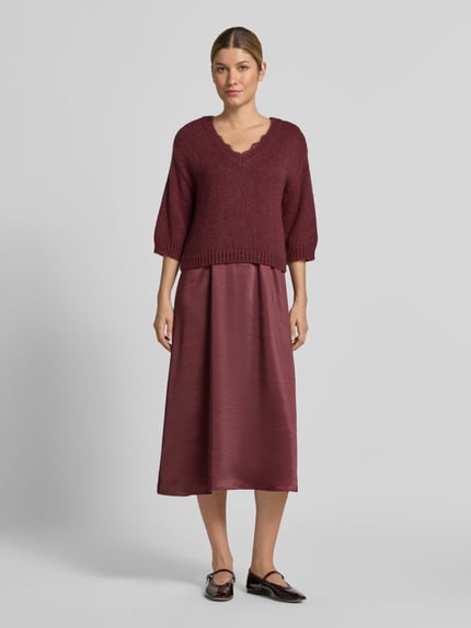 Frauenmodel trägt Figurumspielendes Freizeitkleid mit Spitzenbesatz von ROBE LÉGÈRE in Bordeauxrot mit matter und glänzender Textur, Ganzkörperansicht von vorne.
