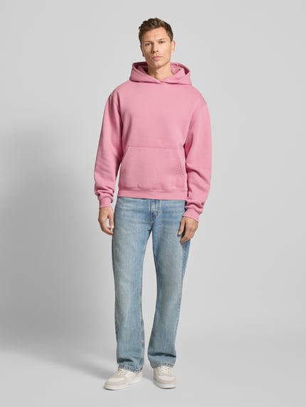 Männermodel trägt Hoodie mit Kapuze Modell 'KAMILIO' von Drykorn in Rosa, Baumwoll-Mix, lockerer Schnitt, Ganzkörperansicht von vorne.