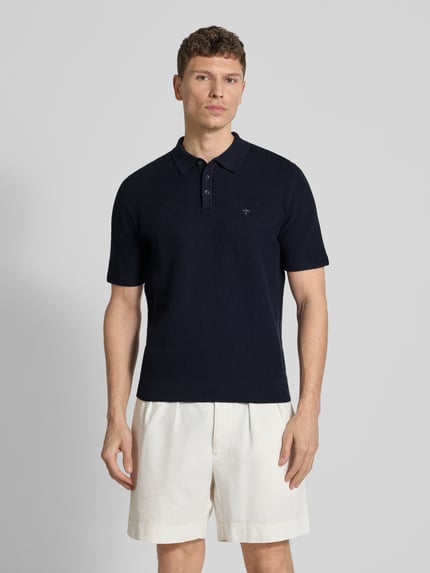Männermodel trägt Regular Fit Poloshirt in Strick-Optik von Fynch-Hatton, dunkelblau, Baumwoll-Mix, Logo-Stitching, Polokragen, Ganzkörperansicht von vorne. Rückenlänge bei Größe M: 67 cm.