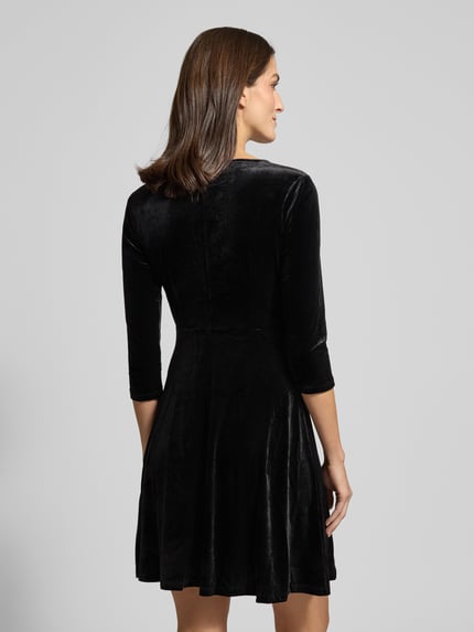 Vrouwenmodel draagt Minikleid met 3/4-mouw model 'VEFLY' van Vila in zwart fluweel, getailleerde pasvorm, achterkant hele lichaam.