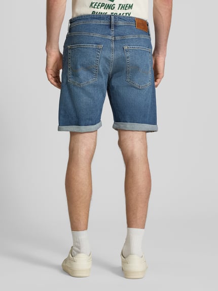 Männermodel trägt Regular Fit Jeansshorts mit Umschlag Modell 'RICK' von Jack & Jones aus Baumwoll-Elasthan-Mix, Eingrifftaschen, Rückansicht Ganzkörperansicht. Bundweite bei Größe M: 42 cm, Innenbeinlänge bei Größe M: 21 cm.