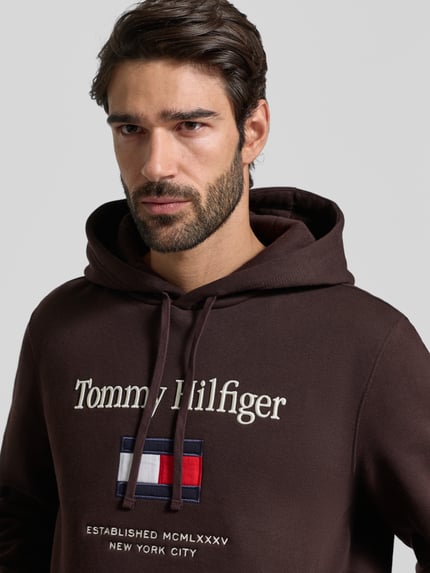 Männermodel trägt Regular Fit Hoodie aus Baumwoll-Mix von Tommy Hilfiger, Optik:Unifarben, Label-Schriftzug, Label-Stitching, Sweat, Nahaufnahme Oberkörper