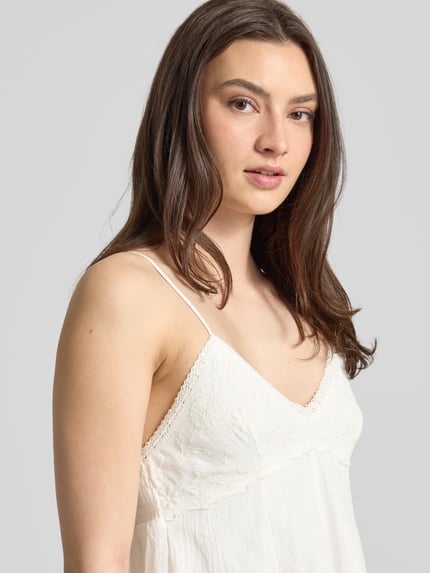 Vrouwenmodel draagt mini-jurk uit puur katoen model 'PANOLA' van Only, effen kleuren, getailleerd, V-hals, smokinzet, borduursel, verstelbare spaghettibandjes, look: effen, detailopname bovenlichaam.