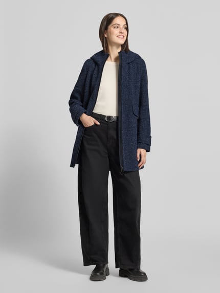 Frauenmodel trägt Mantel mit Kapuze von GIL BRET in Melange-Optik, strukturierte Bouclé-Textur, Longline, Taschen, vorne Ganzkörperansicht.