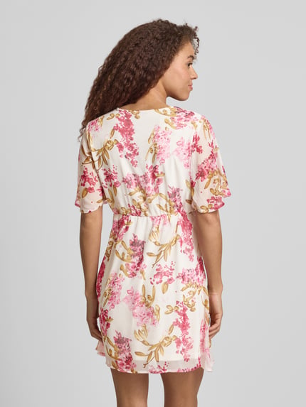 Frauenmodel trägt Minikleid aus Crêpe-Chiffon Modell 'STAR-SUA' von Only mit Florales-Allover-Muster, Tailliert, V-Ausschnitt, Schmetterlingsärmel, Materialverarbeitung: Crêpe-Chiffon, Farbgestaltung in Rosa und Beige, Ganzkörperansicht Rückansicht.