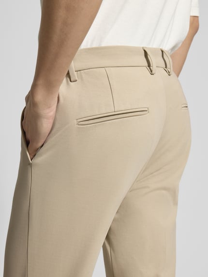 Männermodel trägt Regular Fit Stoffhose aus Baumwoll-Mix von Drykorn in Beige mit Gesäßtaschen, Detailaufnahme Rückenansicht