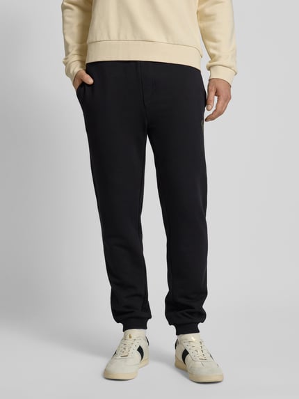 Männermodel trägt Oversized Jogginghose aus reiner Baumwolle Modell 'WEI_CNY' von BOSS in Schwarz, unifarben, Ganzkörperansicht von vorne.