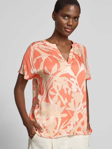 Frauenmodel trägt Blusenshirt aus Viskose im Allover-Look von Milano Italy in Orange-Beige mit V-Ausschnitt, Regular-Fit, Nahaufnahme Oberkörper. Rückenlänge bei Größe 36: 59 cm, Ärmellänge bei Größe 36: 4 cm.