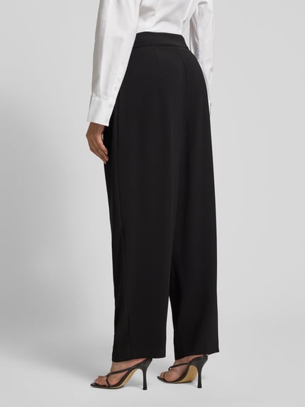 Männermodel trägt czarne Relaxed Fit Hose mit Bundfalten von ARMANI EXCHANGE, szerokość w rozmiarze 36: 38 cm, długość nogawki 76 cm, widok całej sylwetki z tyłu