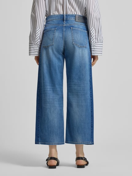 Vrouwenmodel draagt Wide Fit Jeans in verkorte pasvorm model Oria van Cambio, katoenmix, 5-pocketmodel, knoop- en ritssluiting, bandwijdte maat 36: 40 cm, binnenbeenlengte maat 36: 68 cm, blauw met lichte wassingen, rechte vormen, effen textuur. Volledige lichaamsweergave achterkant.