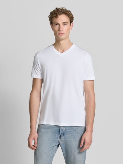 Männermodel trägt Regular Fit T-Shirt aus reiner Baumwolle von s.Oliver RED LABEL in Weiß, glatte Textur, Ganzkörperansicht von vorne.