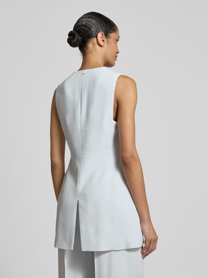 Frauenmodel trägt Slim Fit Longblazer ohne Ärmel Modell 'JULINIAL' von BOSS in Hellgrau, reine Viskose, Rückenschlitz, Ganzkörperansicht Rückansicht.