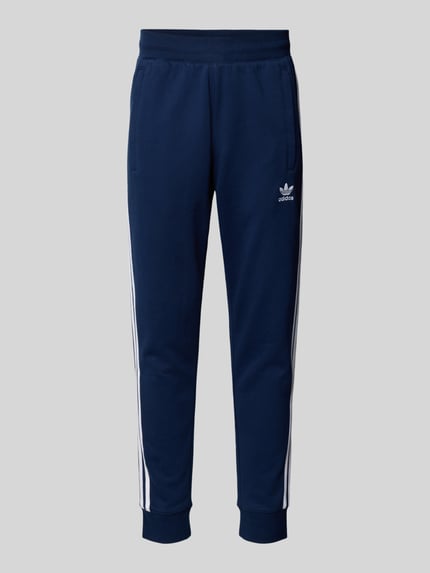 Produktfoto, Spodnie dresowe z elastycznym pasem od adidas Originals, mieszanka bawełny, luźny krój, wpuszczane kieszenie, wyhaftowane logo, długość wewnętrzna nogawki 38 cm dla rozmiaru M.
