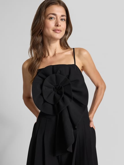 Frauenmodel trägt Jumpsuit mit Spaghettiträgern und Applikation von YAS, Regular Fit, schwarzer Material-Mix, Nahaufnahme Oberkörper.