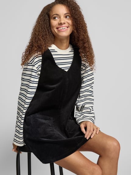 Frauenmodel trägt Minikleid aus Baumwoll-Mix von Marc O'Polo DENIM in Schwarz, unifarben, Cord-Textur, V-Ausschnitt, Ganzkörperansicht von vorne.