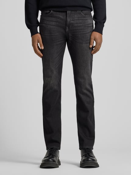 Mannelijk model draagt Slim fit jeans van katoenmix, 5-pocketmodel, denimlook, labelpatch en studs. Model 'DELAWARE BO S.ELECTION' van BOSS Oranje, ganzebodyvooraanzicht.