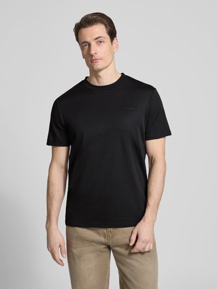 Männermodel trägt T-Shirt mit Rundhalsausschnitt von CK Calvin Klein in Schwarz, Regular Fit, Baumwoll-Mix, Ganzkörperansicht von vorne.