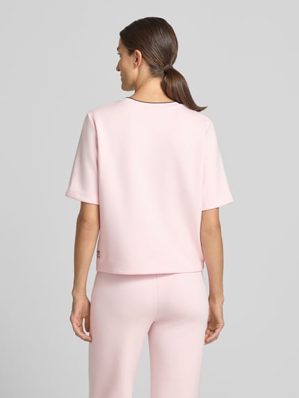 Frauenmodel trägt Relaxed Fit T-Shirt aus Viskose-Mix von Marc Cain in zartem Rosa, leicht strukturierte Oberfläche, Rückenlänge 54 cm, Ganzkörperansicht Rückansicht.