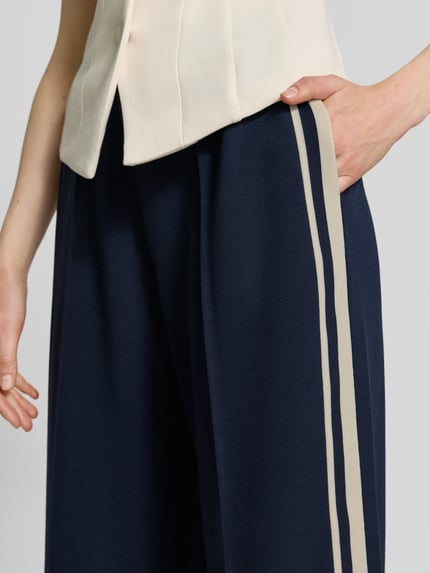 Frauenmodel trägt Jog Pants mit französischen Eingrifftaschen von Jake*s Casual, dunkelblau mit beigen Streifen, Material-Mix mit Stretch-Anteil, Wide Leg Fit, Elastischer Bund, Nahaufnahme Oberkörper.