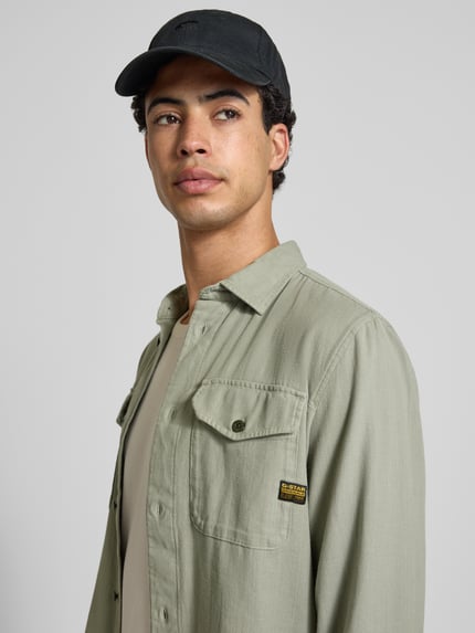 Männermodel trägt Slim Fit Freizeithemd mit Label-Patch Modell 'Marine' von G-Star Raw in Grün, reine Baumwolle, Nahaufnahme Oberkörper.