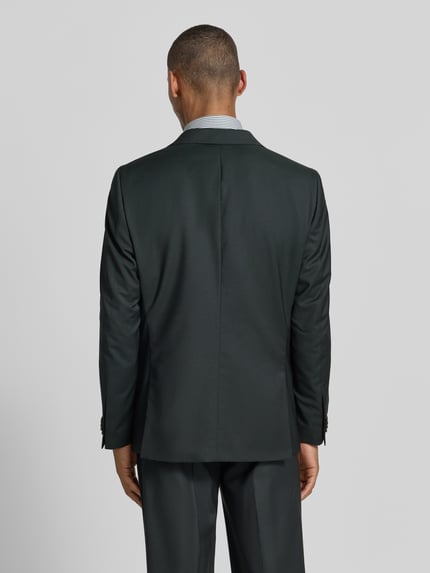 Männermodel trägt Slim Fit 2-knoops colbert model 'Camden' van CG - Club of Gents in zuivere scheerwol met klepzakken, donkere tinten, gladde textuur, ruglengte maat 50: 76 cm, schouderbreedte: 50 cm, mouwlengte: 68 cm, geheel achteraanzicht.