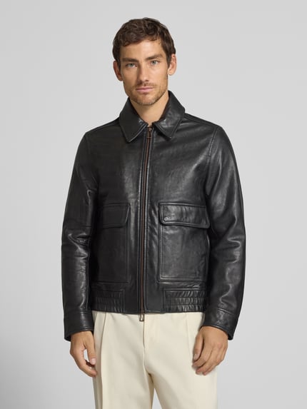 Männermodel trägt schwarze Lederjacke aus Schafsleder mit Pattentaschen von Paul Smith, Bomber Fit, Kentkragen, Ganzkörperansicht von vorne.