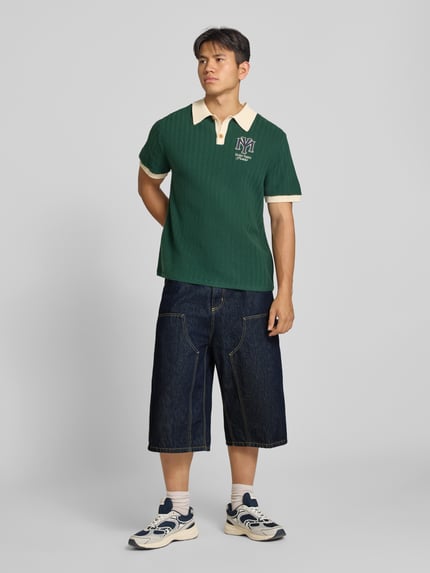 Männermodel trägt Jeans-Bermudas aus reiner Baumwolle Modell 'Double' von Carhartt Work In Progress mit Kontrastnähten, Ganzkörperansicht von vorne, Kontext: Herren Jeans-Bermudas, Loose Fit, 5-Pocket-Design, Bundweite bei Größe M: 44 cm, Innenbeinlänge bei Größe M: 41 cm.