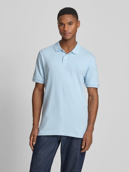 Männermodel trägt Slim Fit Poloshirt mit Label-Stitching von GAP in Hellblau, Baumwoll-Elasthan-Mix, Ganzkörperansicht von vorne.