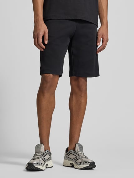 Männermodel trägt schwarze Shorts mit elastischem Bund von EA7 Emporio Armani aus Baumwoll-Mix, Regular Fit, Nahaufnahme Oberschenkel.