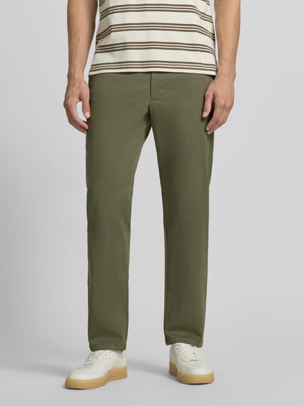 Mężczyzna nosi Hose mit Gesäßtaschen von Christian Berg Men w kolorze oliwkowym, mieszanka bawełny i elastanu, krój slim fit, wpuszczane kieszenie, szerokość w rozmiarze 50: 45 cm, długość wewnętrzna nogawki w rozmiarze 50: 80 cm, Ganzkörperansicht von vorne.