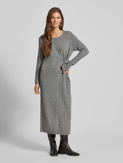 Frauenmodel trägt Relaxed Fit Kleid aus Woll-Mix in Strick-Optik Modell 'Protect' von Comma, grau, langärmelig, Zierschleife, Rundhalsausschnitt, Ganzkörperansicht von vorne. Kontext: Damen Kleid, Modal-Anteil, Rückenlänge 125 cm, Brustweite 46 cm, Ärmellänge 61 cm.