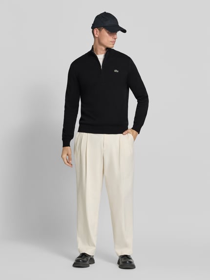 Männermodel trägt Pullover mit Logo-Patch Troyer von LACOSTE, look: effen, structuur, logopatch, detail: ritssluiting, schipperskraag, hooggesloten, mouwen: lang, mouwboord: geribd, rompzoom: geribd, materiaalverwerking: fijngebreid, ganzkörperansicht von vorne.
