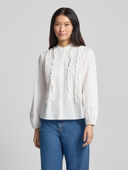 Frauenmodel trägt Regular Fit Bluse aus Baumwoll-Mix mit Rüschenbesatz von MORE & MORE in Weiß, Stehkragen, Jeans, Ganzkörperansicht von vorne. Rückenlänge 65 cm, Ärmellänge 60 cm, elastischer Baumwoll-Mix, langärmelig, durchgehende Knopfleiste.