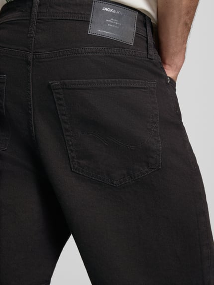 Männermodel trägt Relaxed Fit Jeansshorts Modell 'TONY' von Jack & Jones aus schwarzem Baumwoll-Elasthan-Mix mit Eingrifftaschen, Detailaufnahme Rückansicht. Bundweite 42 cm, Innenbeinlänge 21 cm bei Größe M.