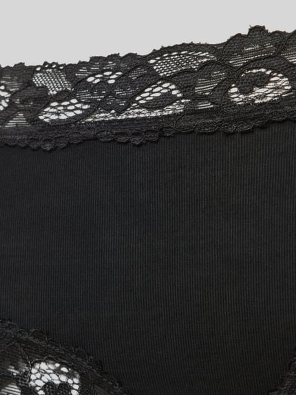 Frauenmodel trägt schwarze Slim Fit Panties mit Spitzenbesatz von Skiny, elastischer Micromodal-Mix, florale-Optik, Nahaufnahme Hüfte.