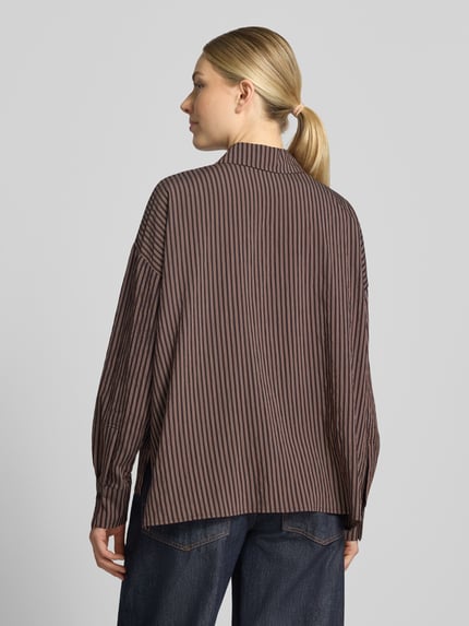 Vrouwenmodel draagt Relaxed Fit blouse met all-over look van DRYKORN, Viscosemix, Model 'CLOELIA', overhemdkraag, knoopsluiting, schouders met verlaagde mouwinzet, ruglengte maat 36 74 cm, mouwlengte 51 cm, donkere en lichte strepen, zachte textuur, donkere jeans, volledige achteraanzicht.