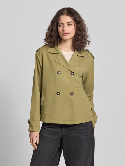 Modelka nosi Regular Fit Trenchcoat-Jacke mit Reverskragen Modell 'HANNAH' od Only, oliwkowa, długie rękawy, przód, krój regular fit, elegancka faktura, guziki, kieszenie boczne, pagony na ramionach, gładka struktura, widok całej sylwetki z przodu