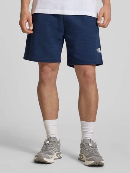 Männermodel trägt Shorts mit Logo von The North Face aus dunkelblauem Baumwoll-Mix, Regular-Fit, elastischer Bund, Ganzkörperansicht von vorne.