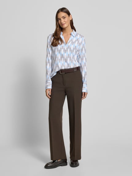 Modelka kobieca nosi Regular Fit Bluse im Allover-Look mit V-Ausschnitt od Herzensangelegenheit, niebiesko-biały wzór, materiał z domieszką stretchu, prosty krój, kołnierzyk, widok całej sylwetki z przodu.