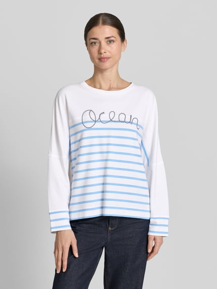 Frauenmodel trägt Sweatshirt im Allover-Look mit Rundhalsausschnitt von Marc Cain aus Baumwoll-Elasthan-Mix, Relaxed-Fit, Weiß mit blauen Streifen, glatte Oberfläche, Ganzkörperansicht von vorne.