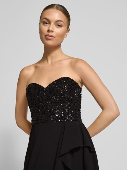 Kobiece model nosi Sukienka wieczorowa z falbanami i cekinami od Adrianna Papell, czarna, kopertowy styl, odkryte ramiona, detal z cekinami, szerokość klatki piersiowej 38 cm, długość tyłu 152 cm, Linia A, Nahaufnahme górnej części ciała.