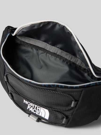 Produktfoto, czarna saszetka nerka Bauchtasche mit Logo-Print Modell 'Jester' od The North Face, Główna przegroda z zamkiem błyskawicznym, nadruk z logo, szerokość w rozmiarze 1: 27 cm, długość w rozmiarze 1: 16 cm, głębokość w rozmiarze 1: 9 cm, długość paska: 30 cm, teksturowany materiał